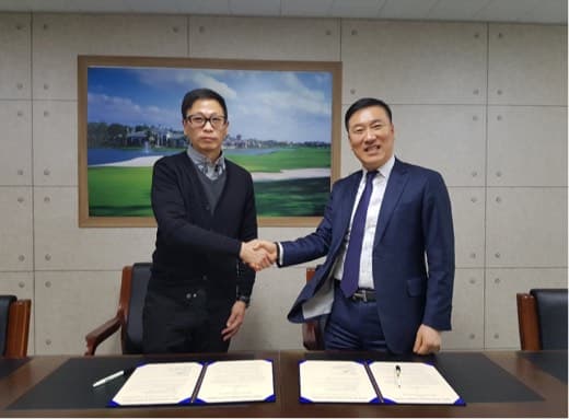 협약서를 사이에 두고 악수하는 두 사람